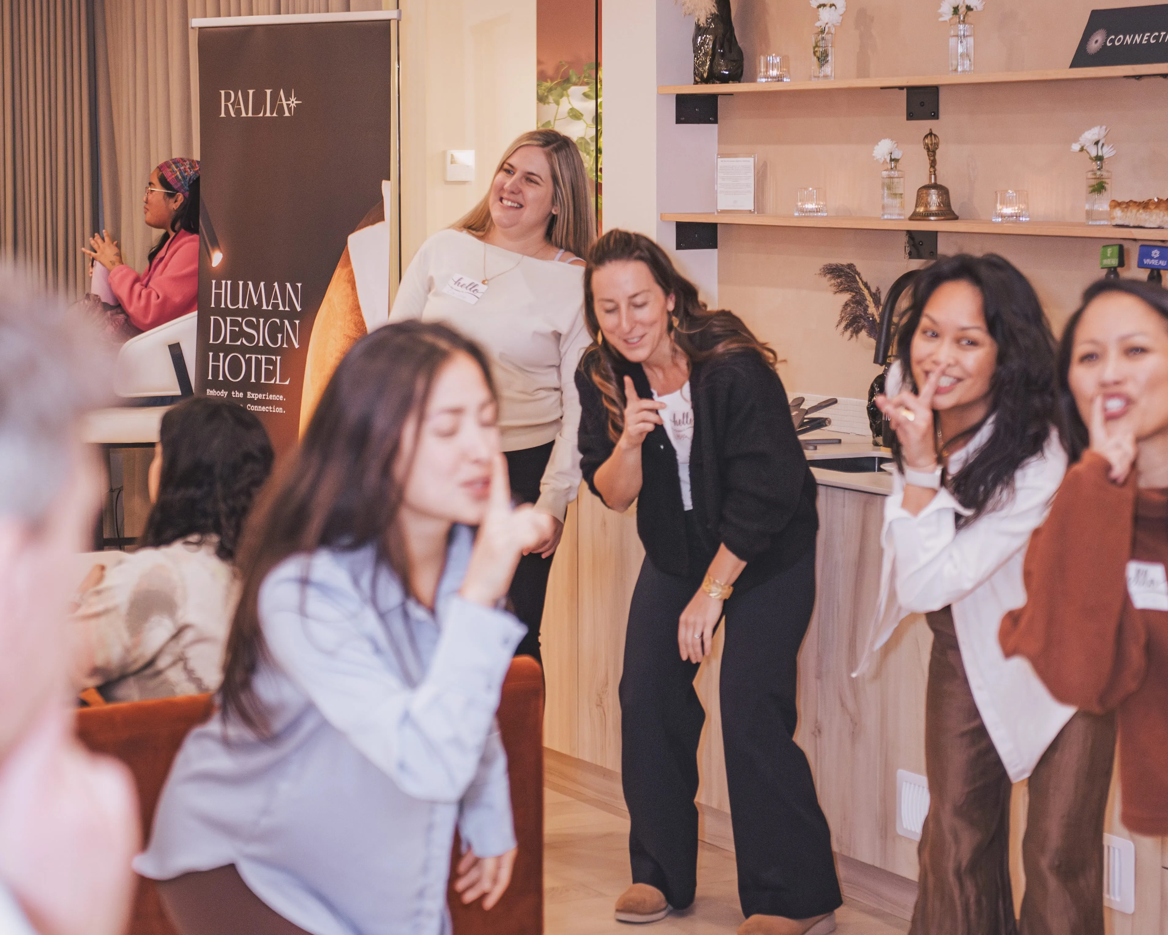Guests laughing together at an event beside the Ralia Human Design Hotel banner in Montreal