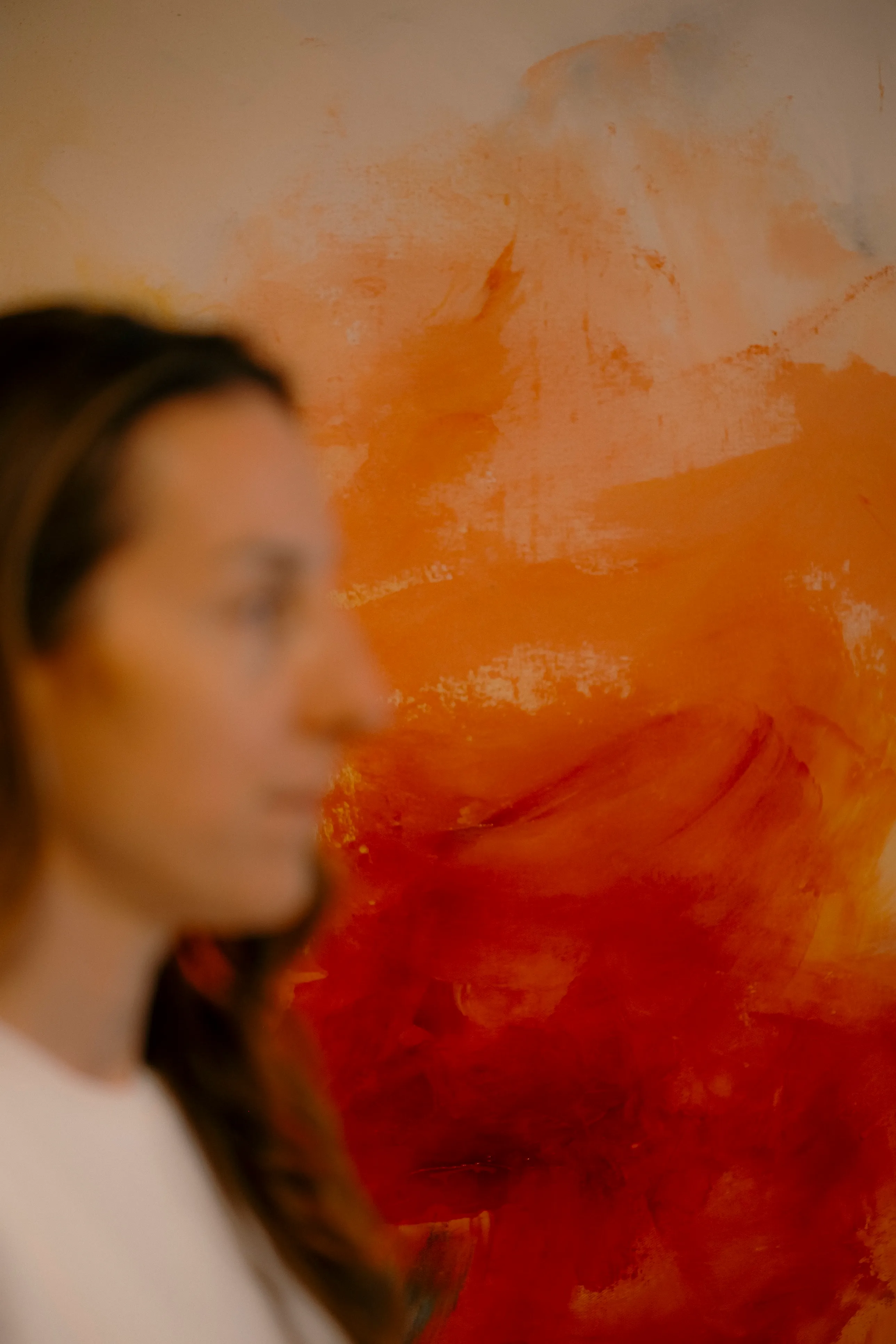 A guest in soft focus beside a bold orange and red abstract painting at Ralia