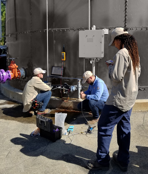EMASS Technicians and site operators check the status of instrumentation on a tank at a treatment plant.