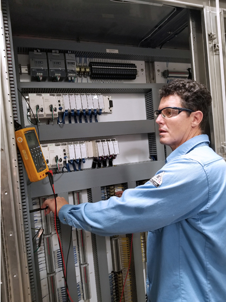 An EMASS technician calibrates instrumentation in a control panel.