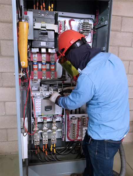 System technician cleaning and running diagnostics on an MCC at a treatment plant.