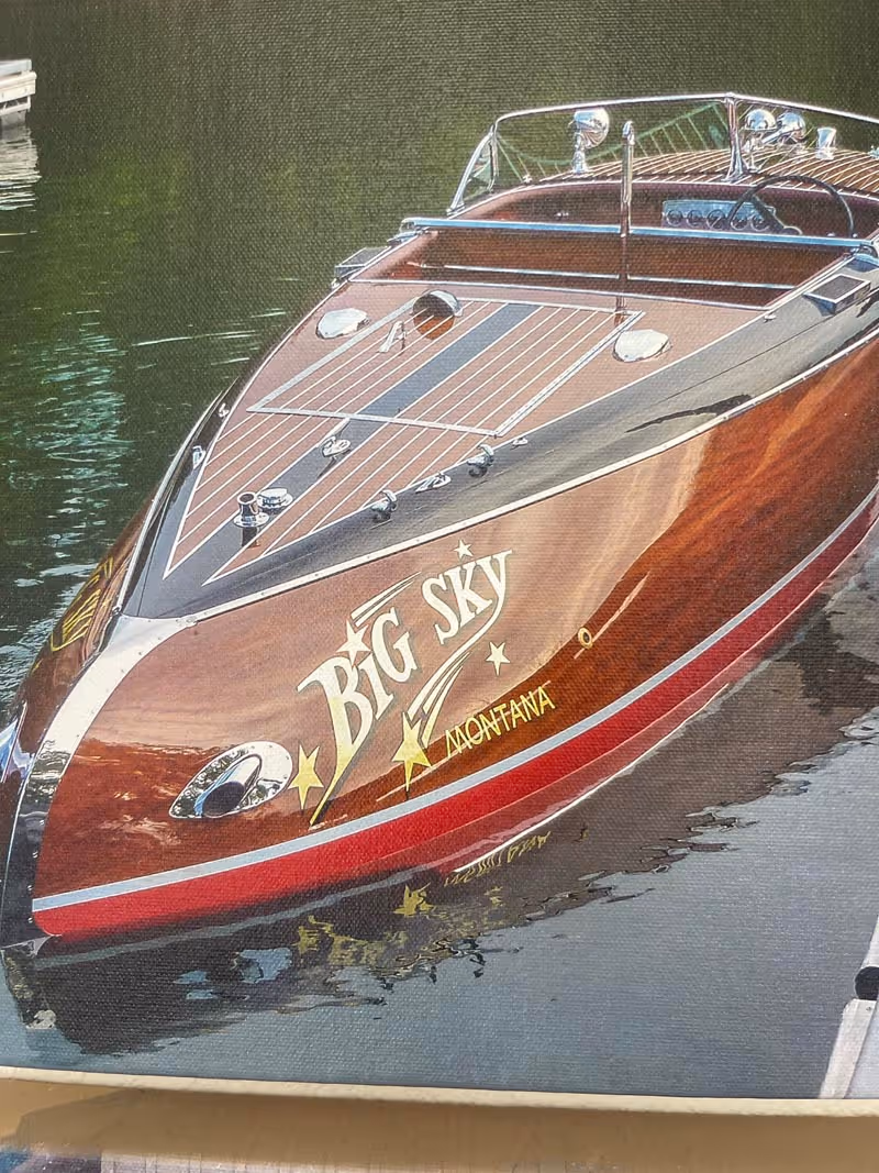 Wooden speedboat named Big Sky Montana docked on calm water.
