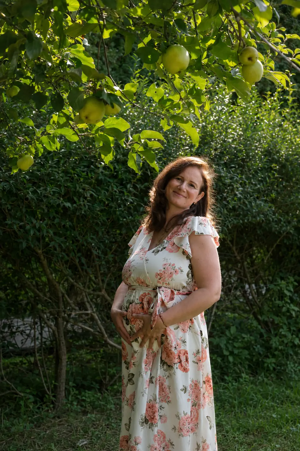 Diana Z. Petrova, founder of Womb Visions, during pregnancy beneath an apple tree