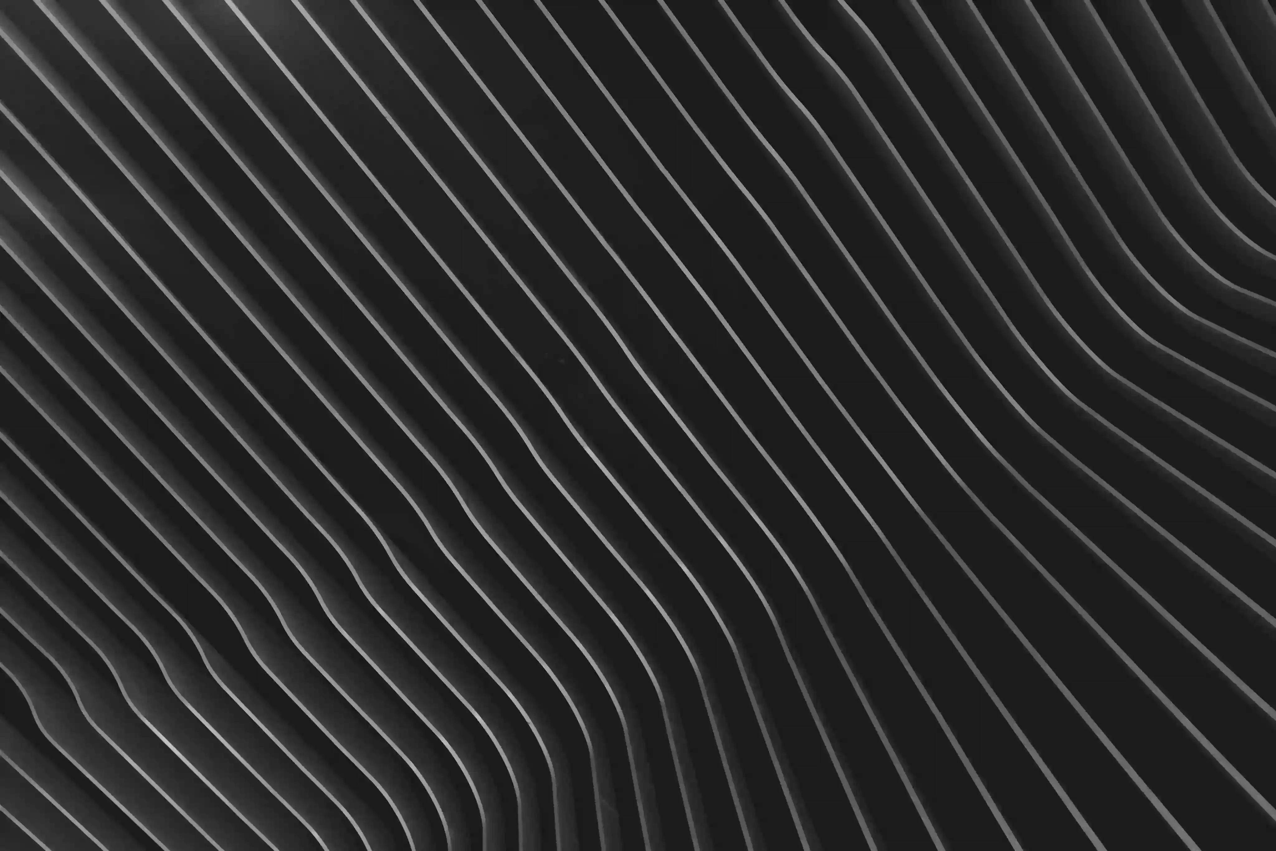 Abstract black surface with evenly spaced, curved white lines creating a wave-like pattern.
