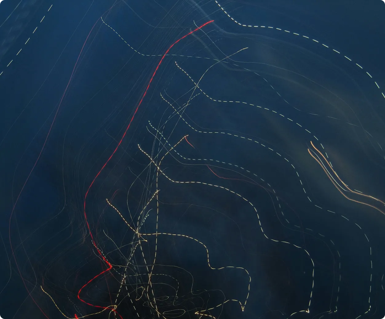 Long exposure photo of multiple boats or ships at sea showing dotted and curved light trails on dark water.