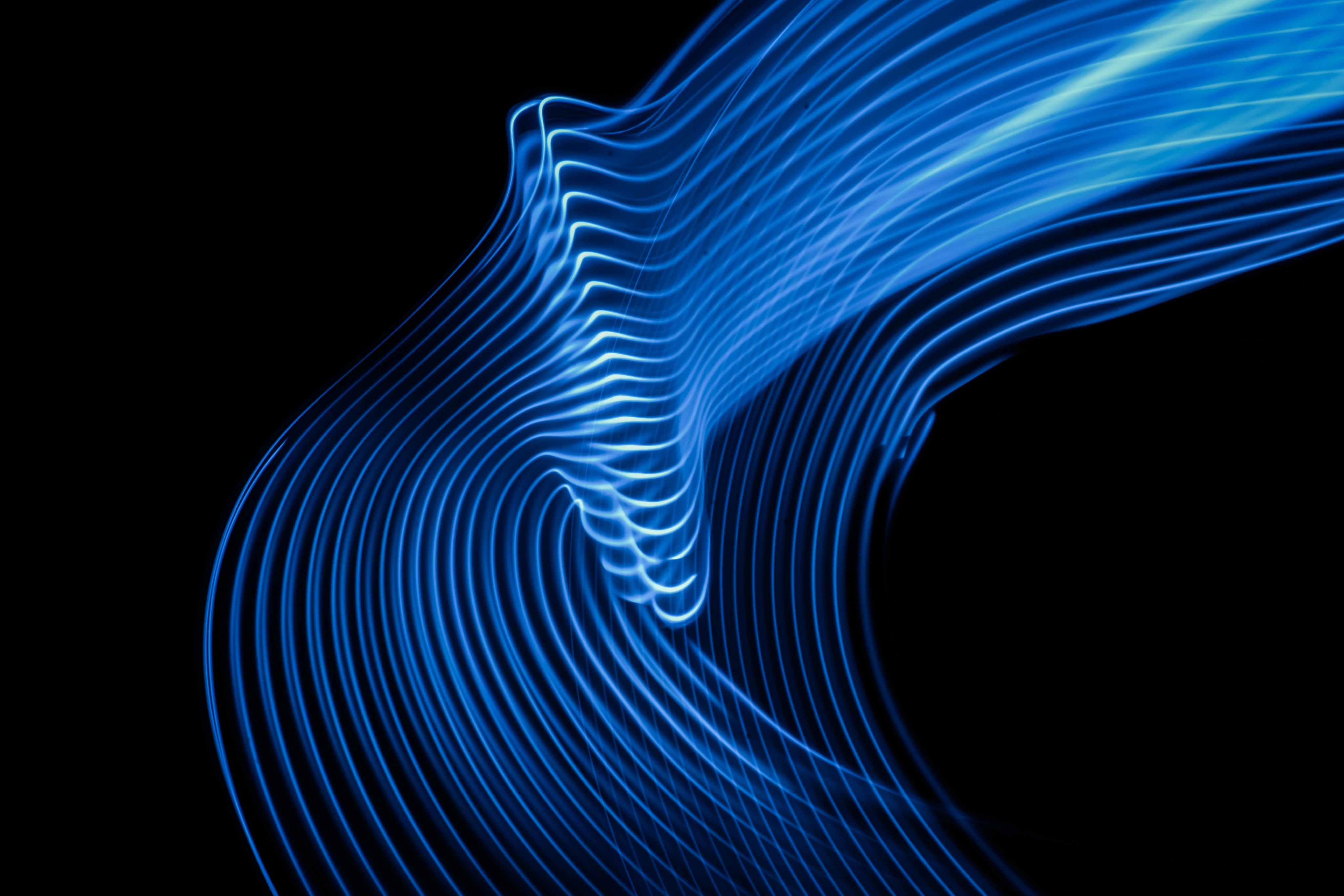 Abstract blue light waves on a black background creating a flowing, curved pattern.