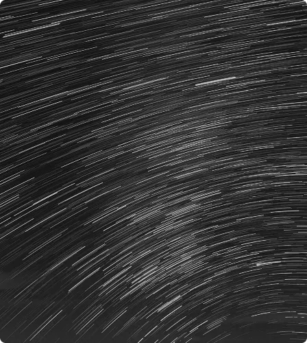 Long-exposure photo of star trails in the night sky forming curved streaks of light.