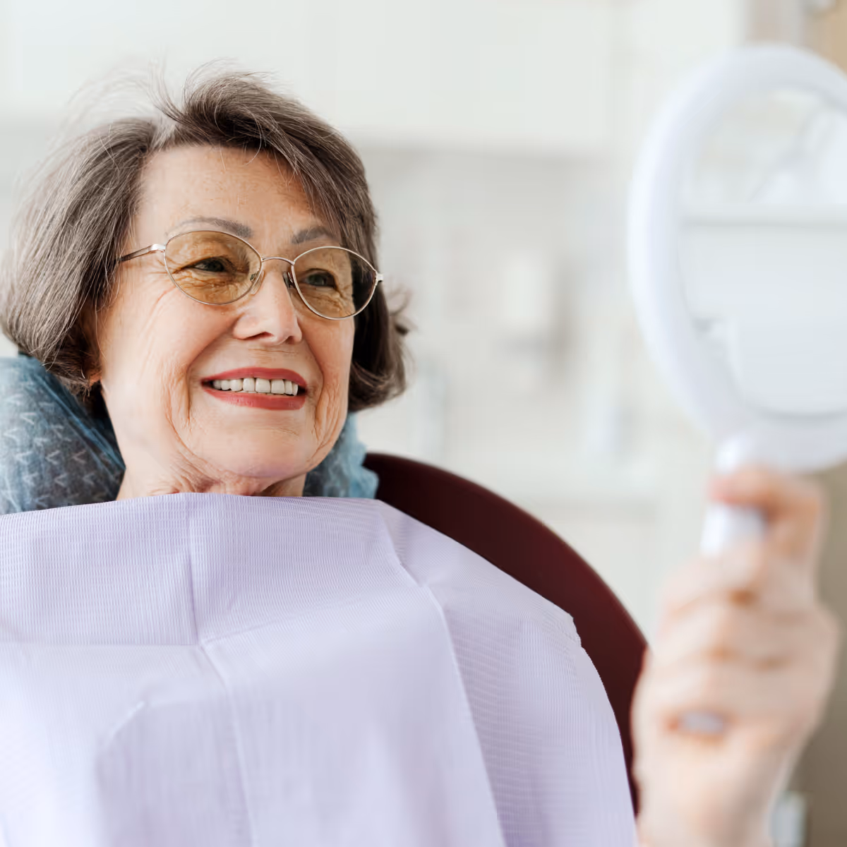 elderly dental patient looks at herself in mirror