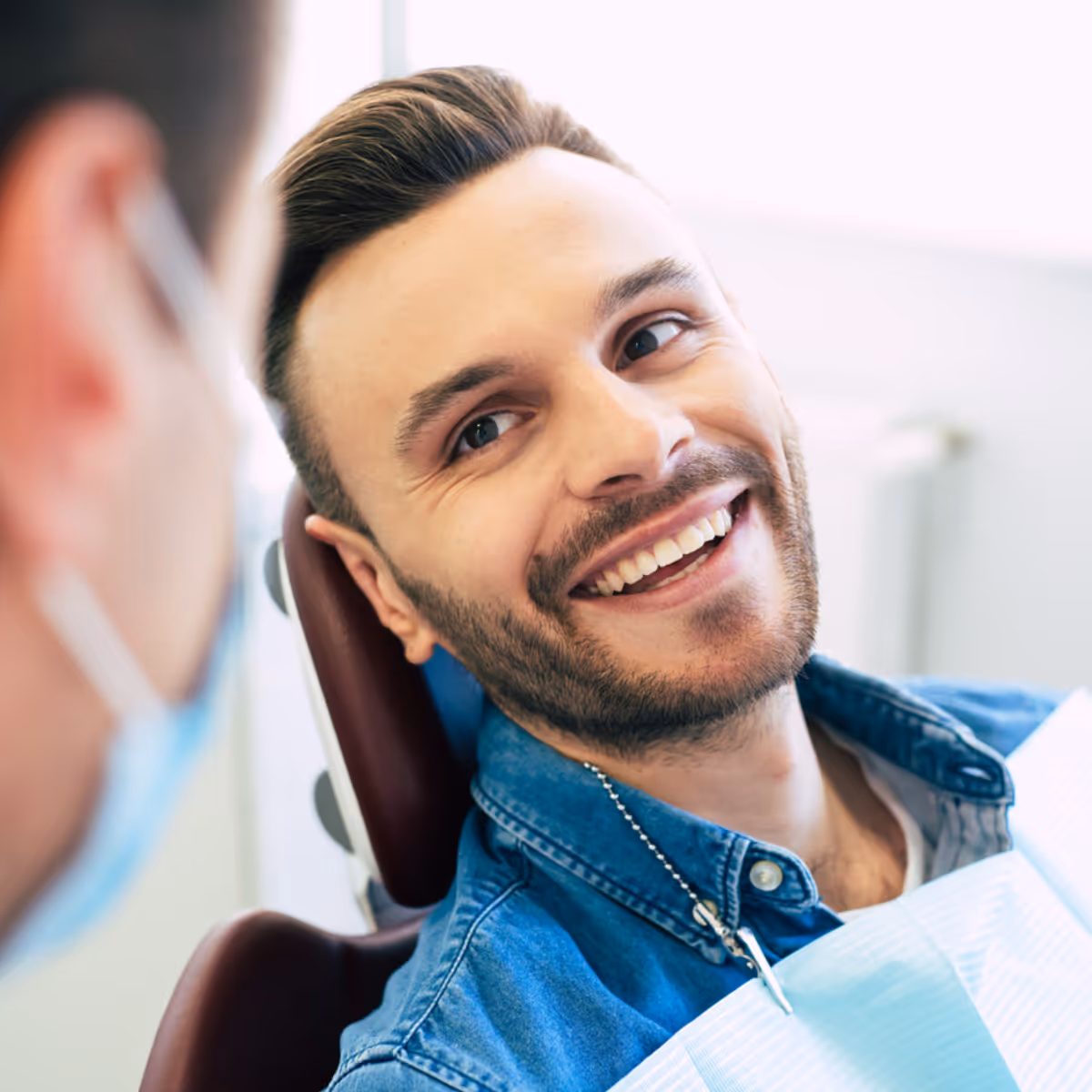 Young man smiling at dentist while in dental chair