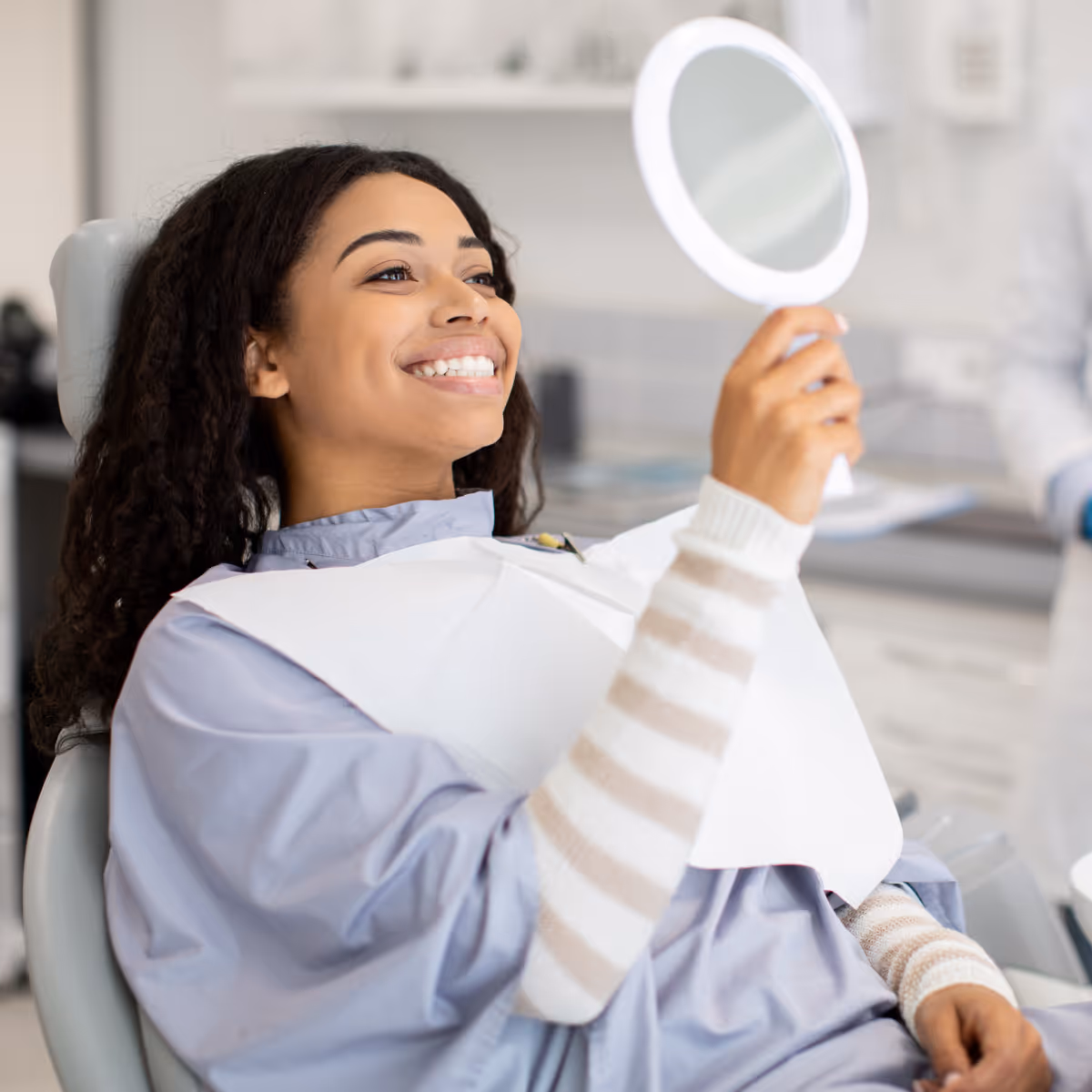Dental patient looks at themselves in mirror while smiling