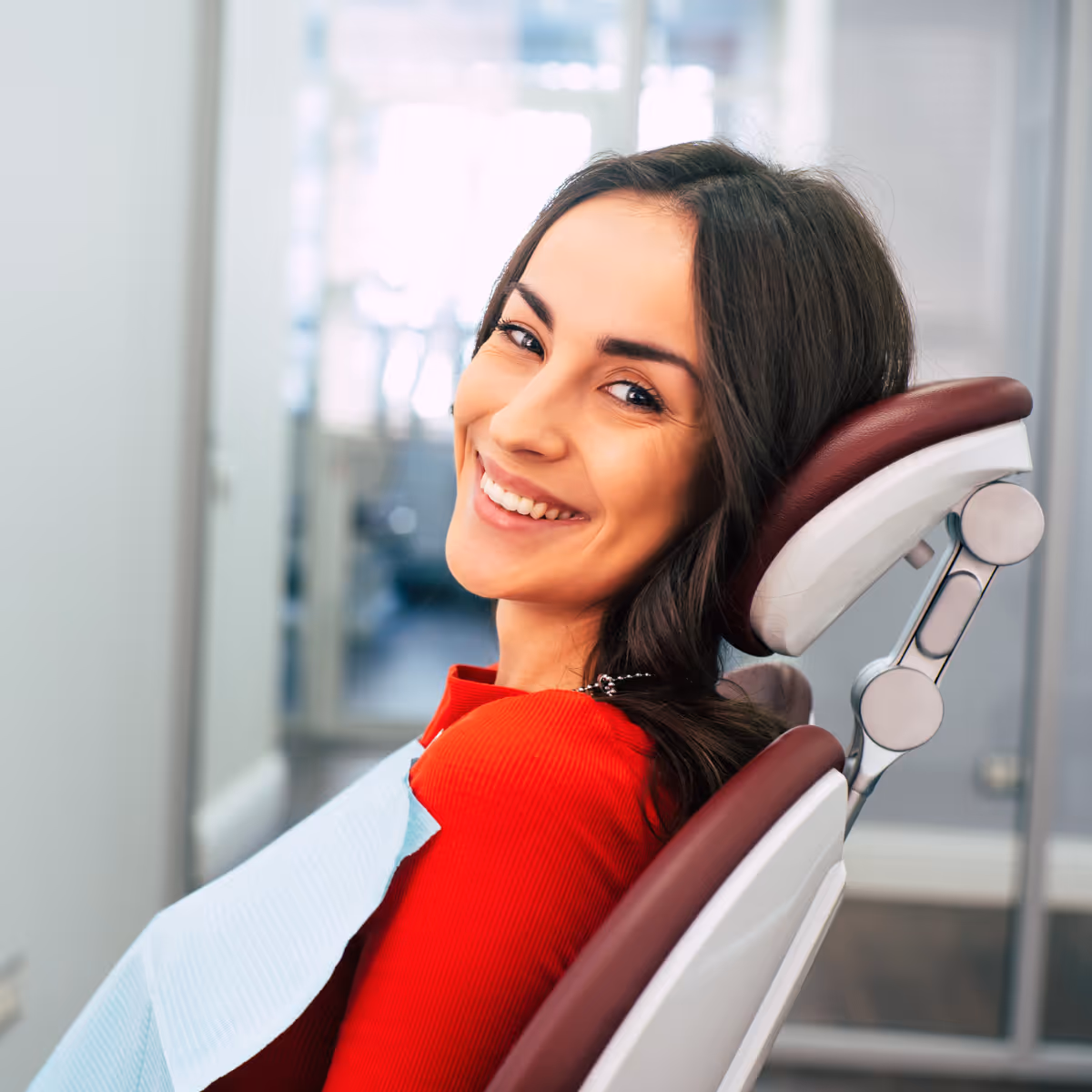 relieved dental patient smiles at camera while sitting in dental chair