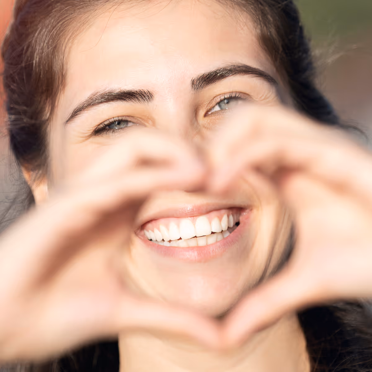 Woman smiling making a heart with her hands