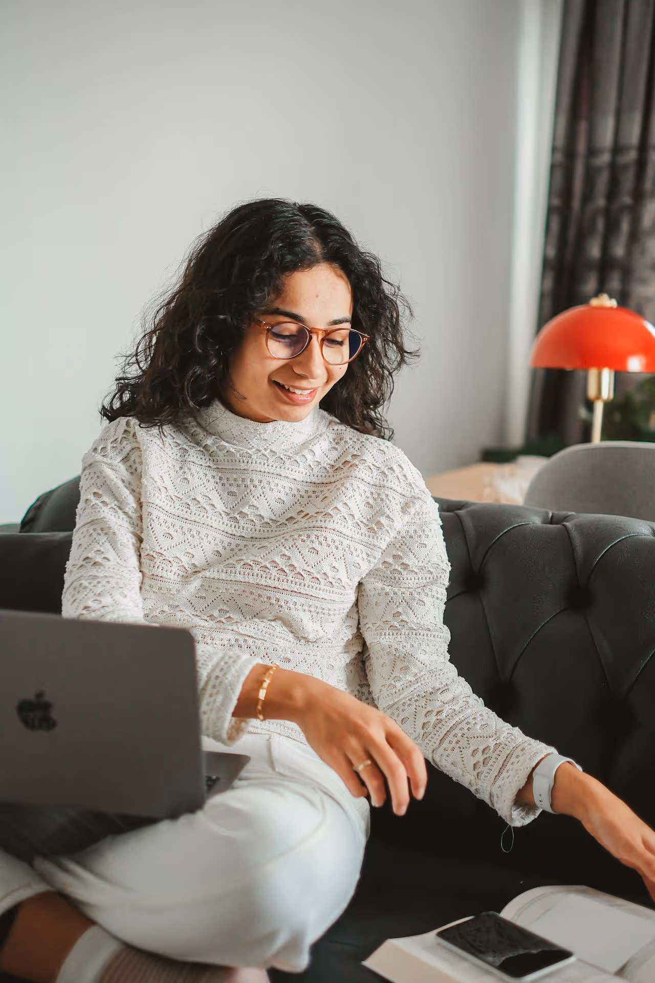 Construction site with workers assembling a gray concrete block retaining wall beside a house, surrounded by trees and gravel.