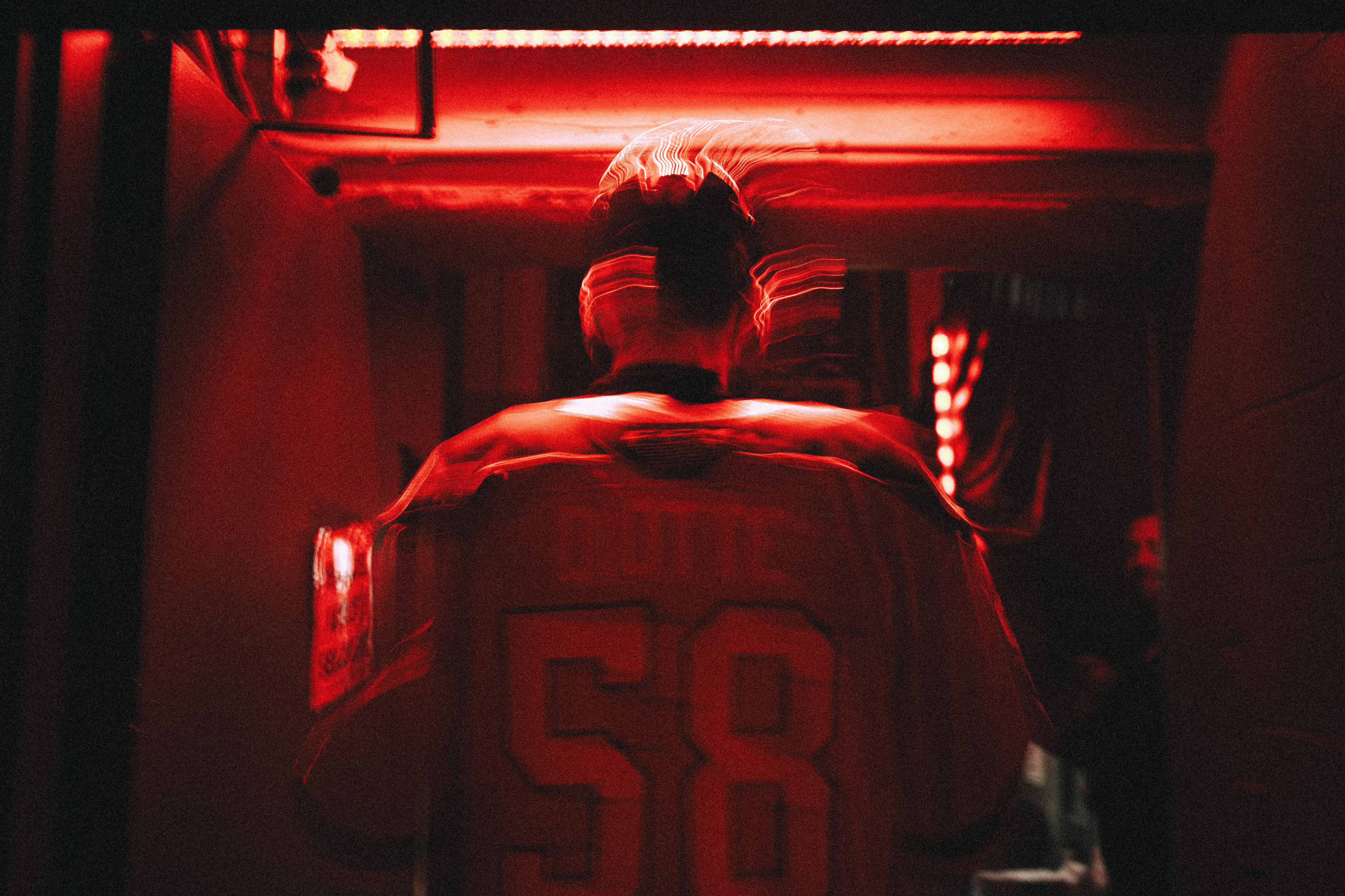 Hockeyeur des Voltigeurs de Drummondville portant le chandail numéro 58 sous lumière rouge dans un couloir sombre.