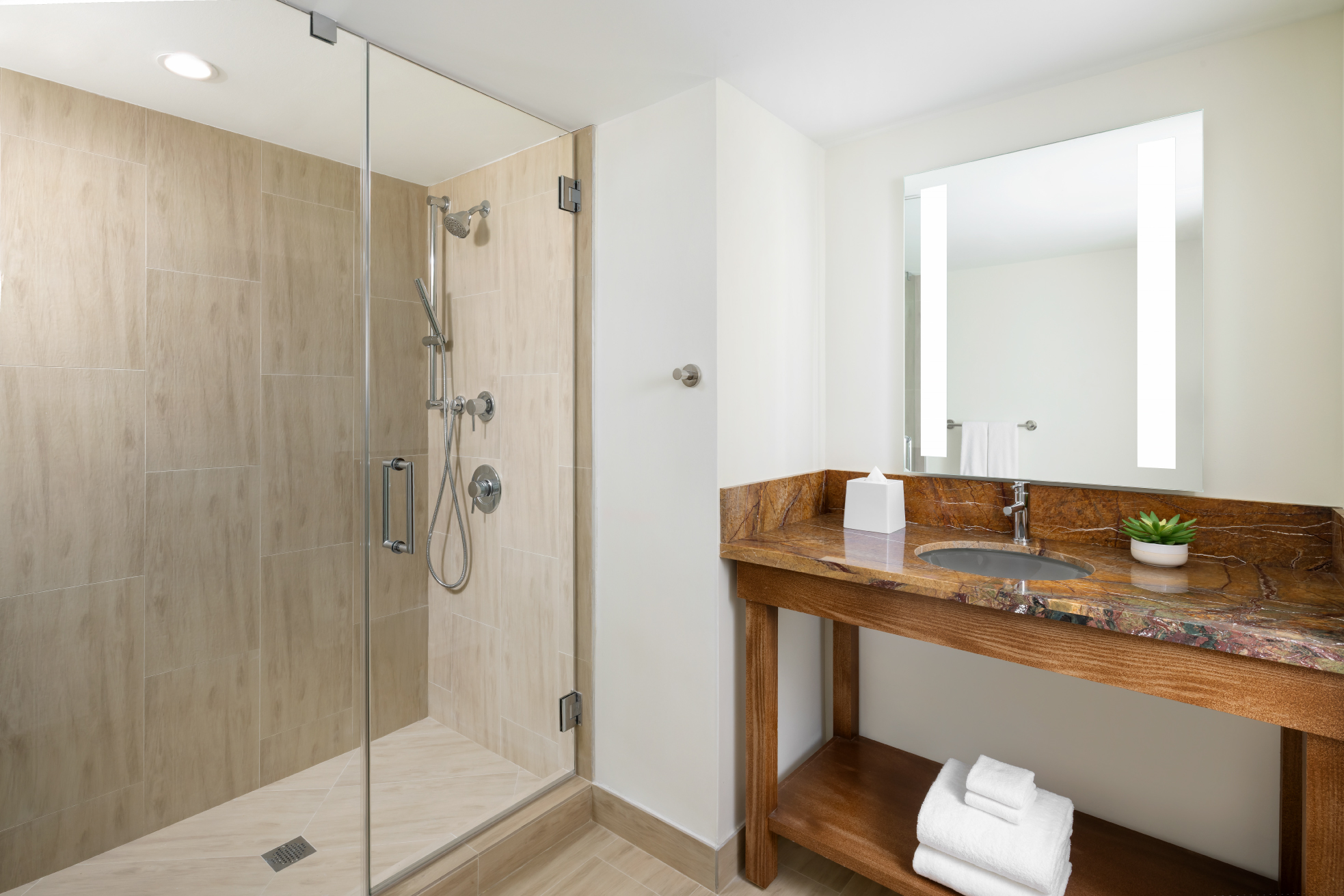upscale bathroom with wooden sink area and glass walk in shower