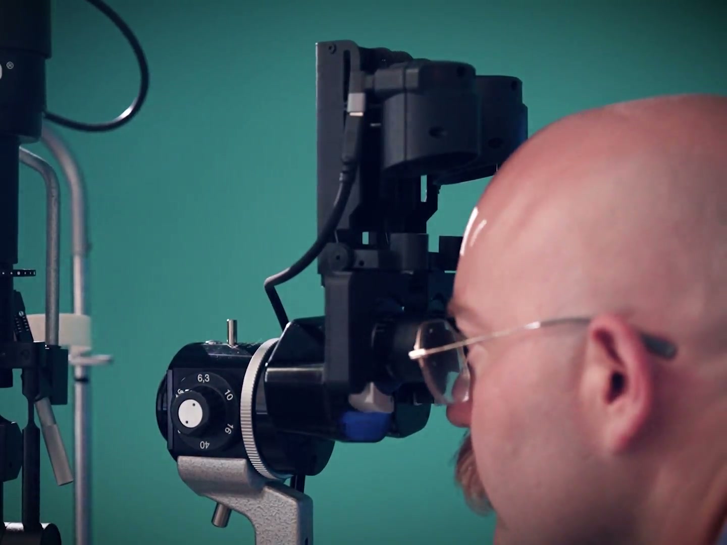 An examiner looks directly through the slit lamp oculars with both VitaPixel SVS cameras flipped up out of the way.