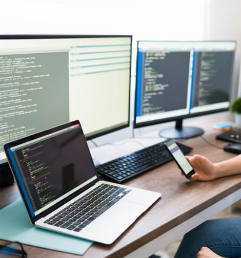 Developer workspace with laptop and code on multiple screens