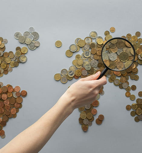 Magnifying glass over coin world map representing global finance