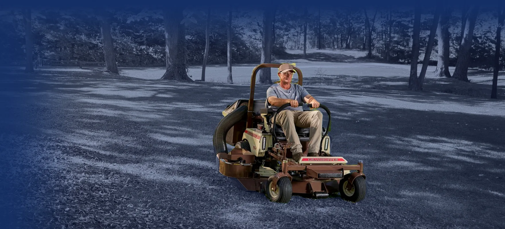 Operator mowing a fall lawn on a Grasshopper zero-turn mower with a leaf collection system