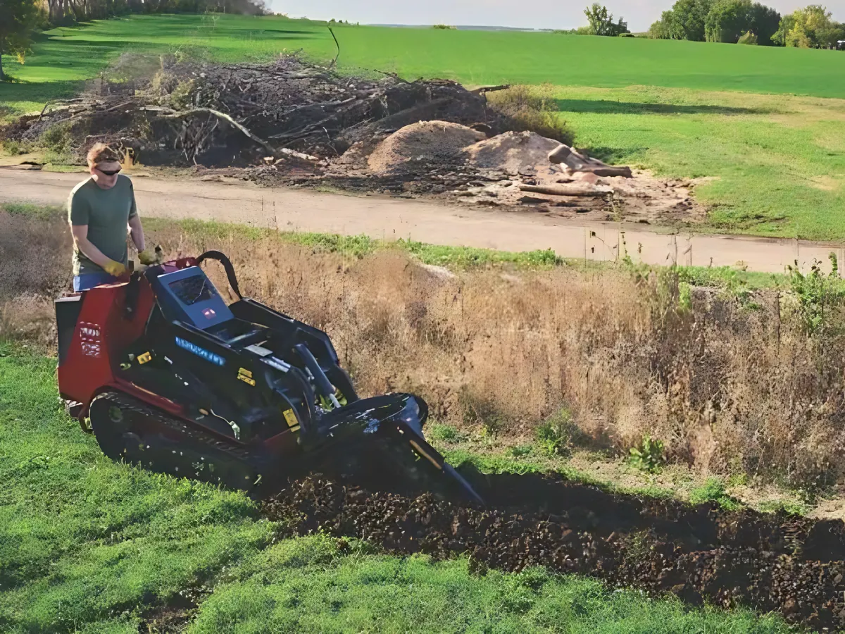 Operator trenching a field edge with a Toro Dingo compact utility loader