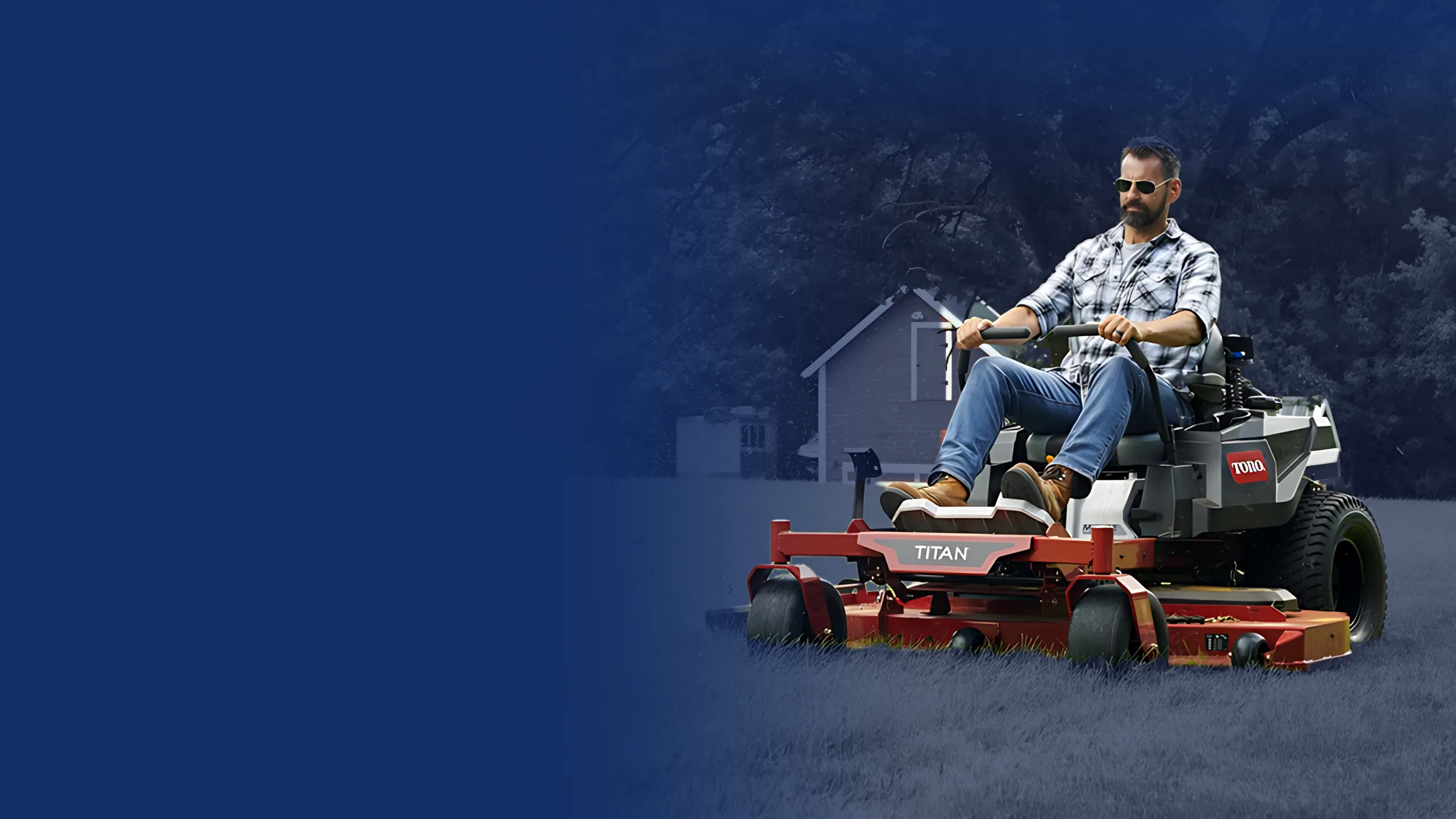 Operator mowing on a Toro Titan zero-turn mower beside a red barn