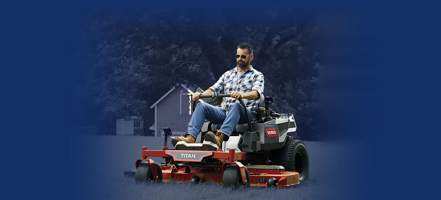 Operator mowing on a Toro Titan zero-turn mower beside a red barn