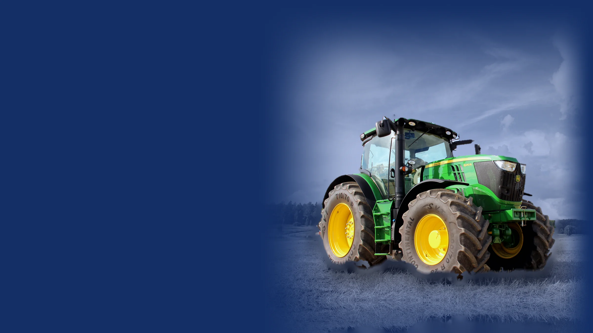 John Deere 6210R tractor parked on a harvested field