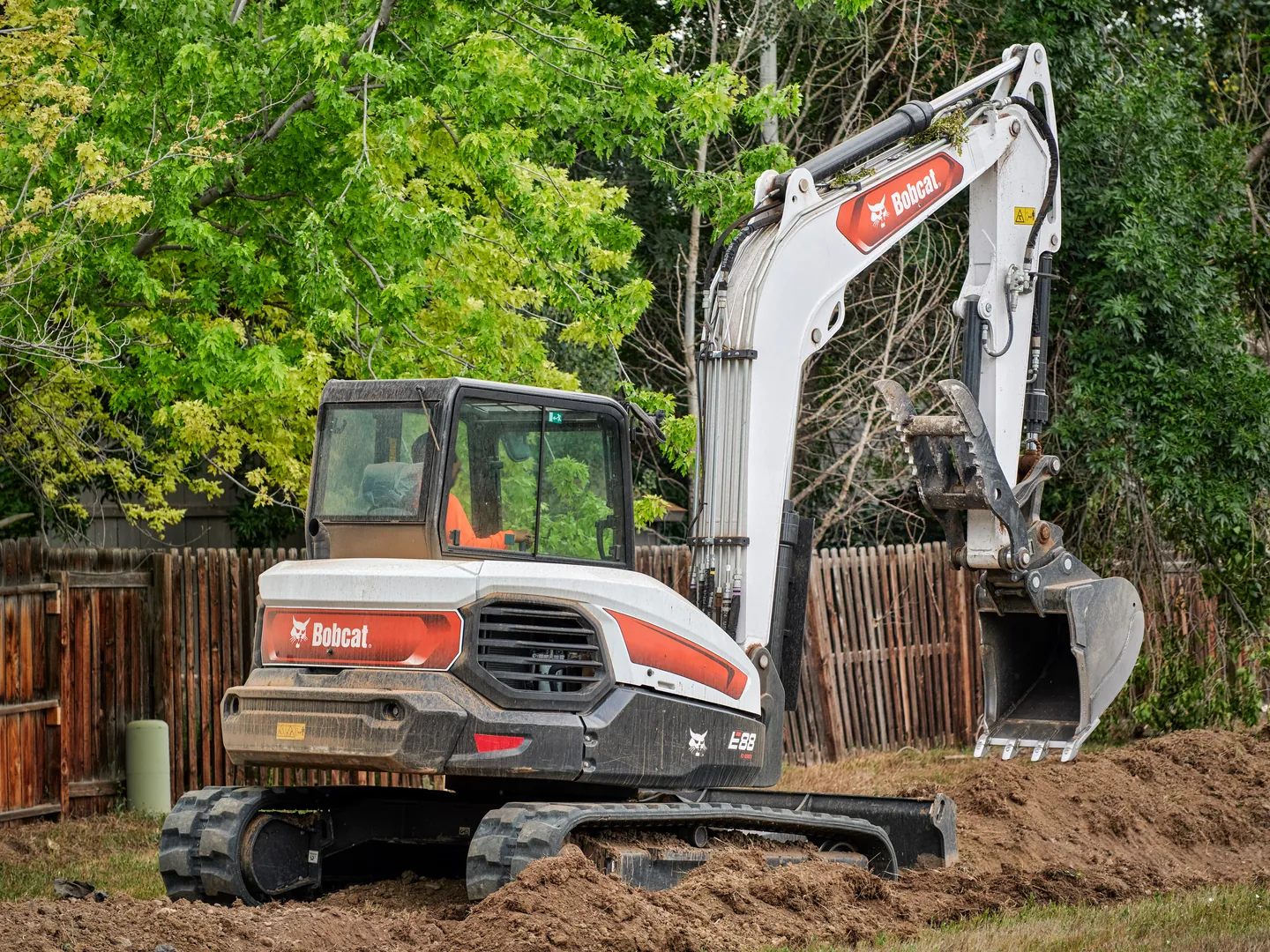 Bobcat E88 compact excavator digging in a residential backyard