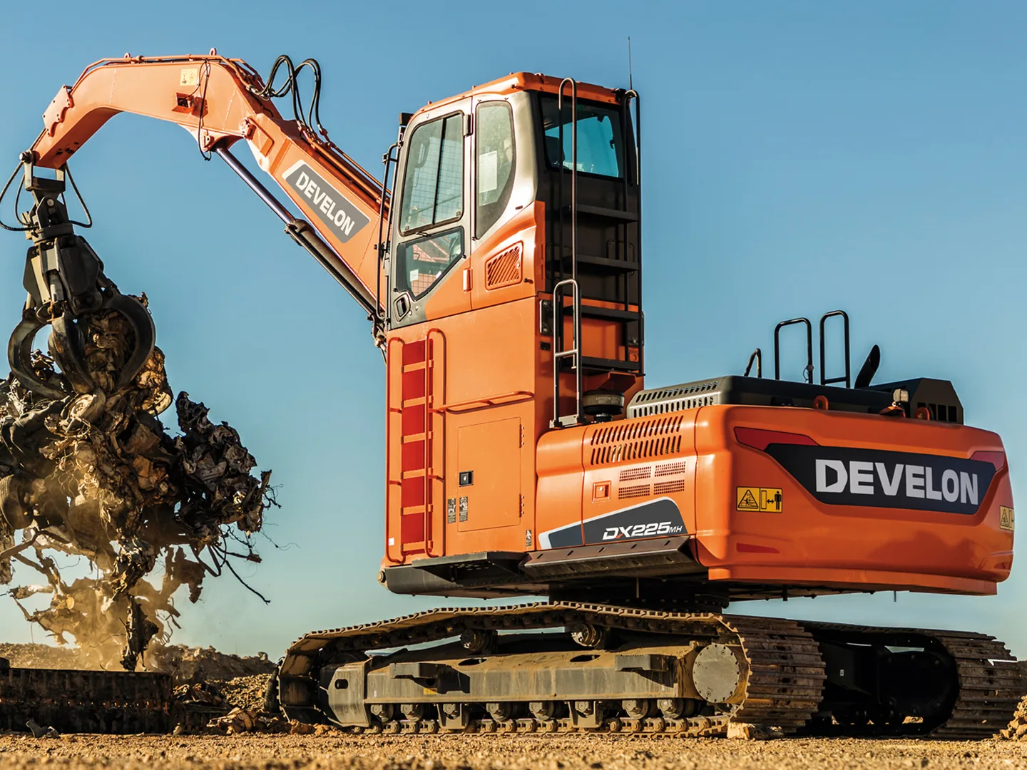 Develon DX225MH material handler lifting scrap metal with a grapple