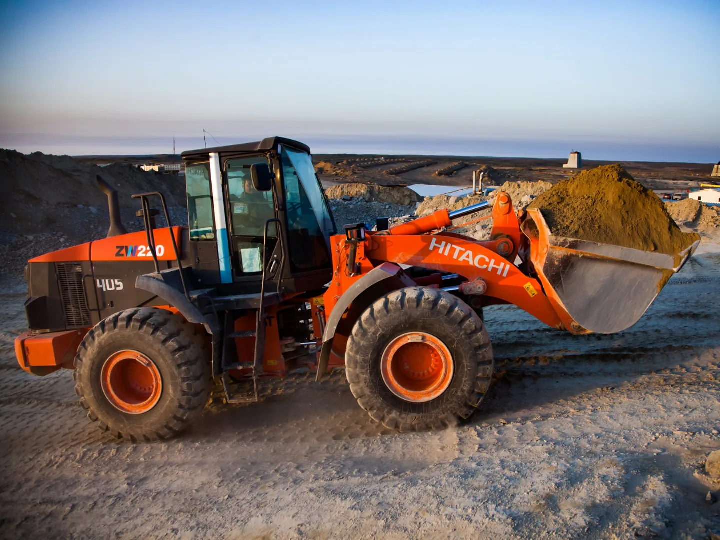 Hitachi ZW220 wheel loader carrying a full bucket of dirt