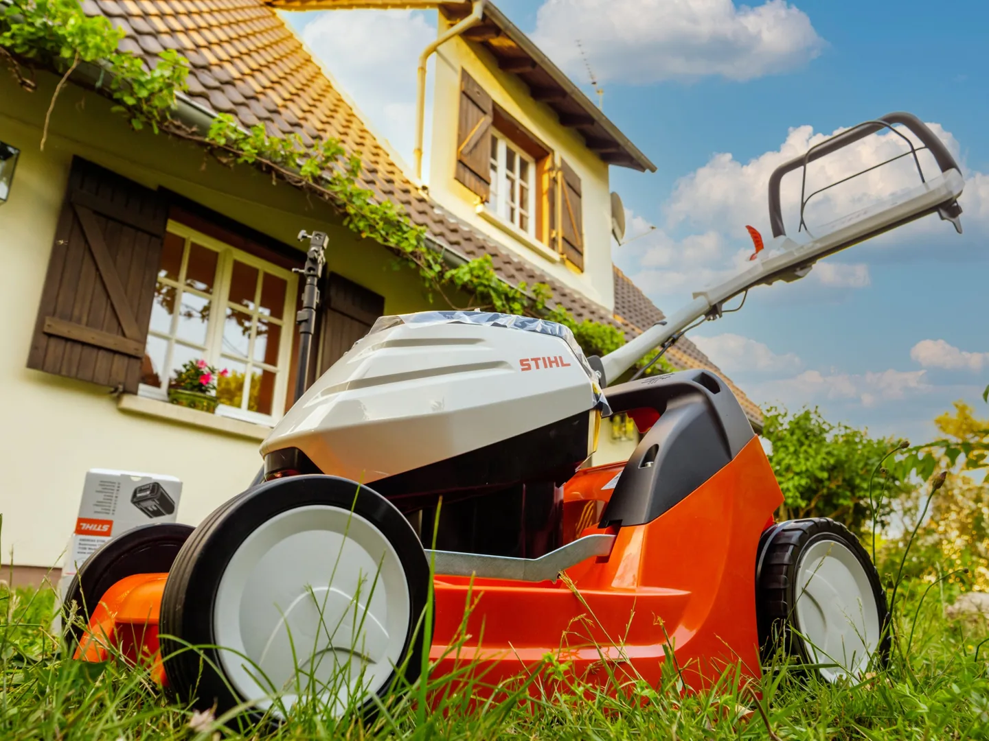 STIHL battery lawn mower on the grass in front of a house