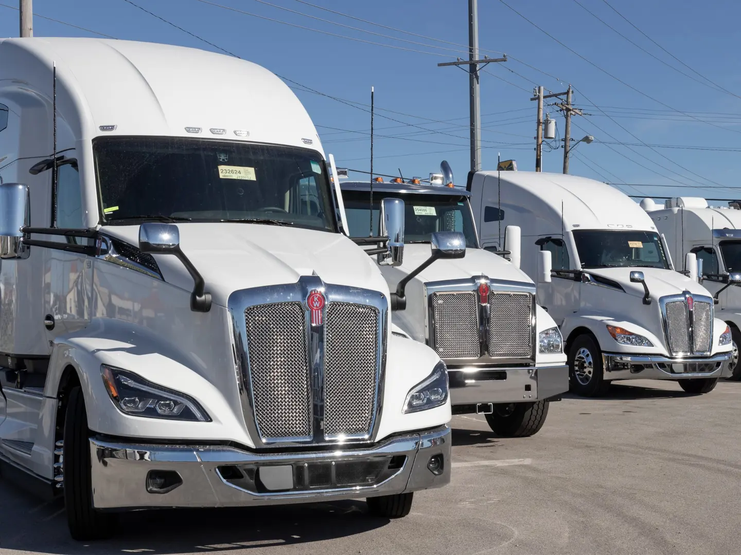 Row of new white Kenworth T680 trucks on a dealer lot