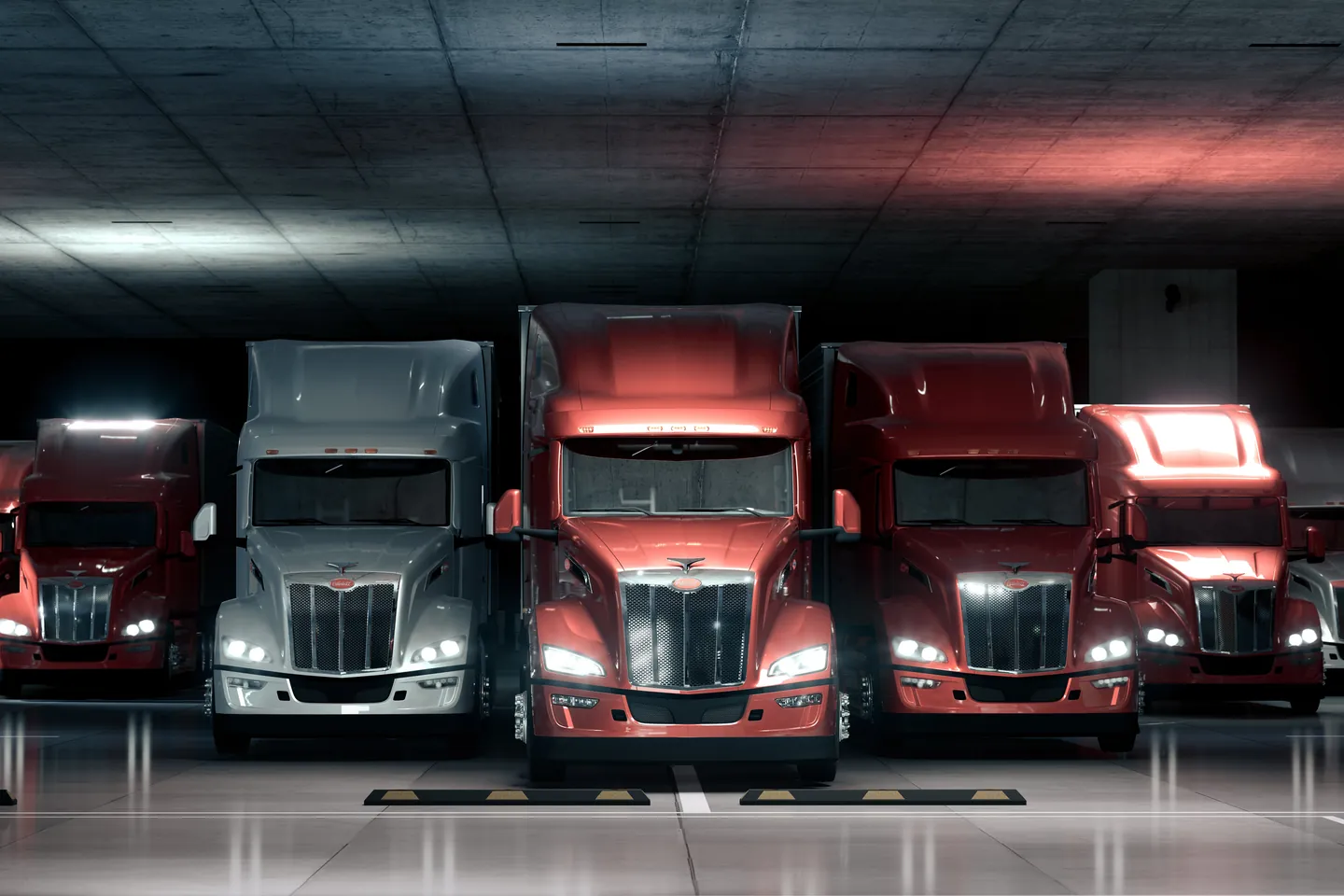 Row of red and white Peterbilt trucks with their headlights on in a parking garage