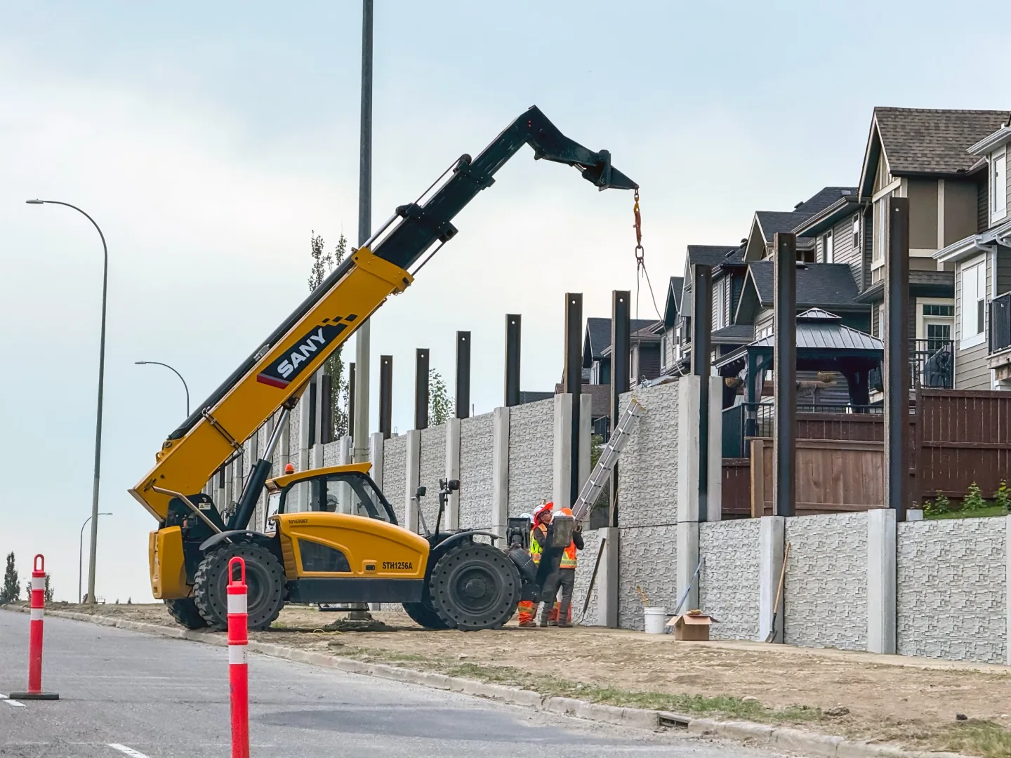 SANY STH1256A telehandler setting posts for a sound wall while a crew guides the load