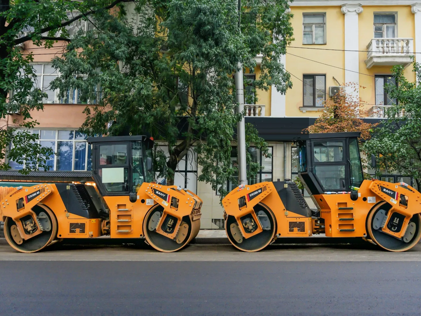 Two SANY STR130C double drum rollers parked on a freshly paved city street