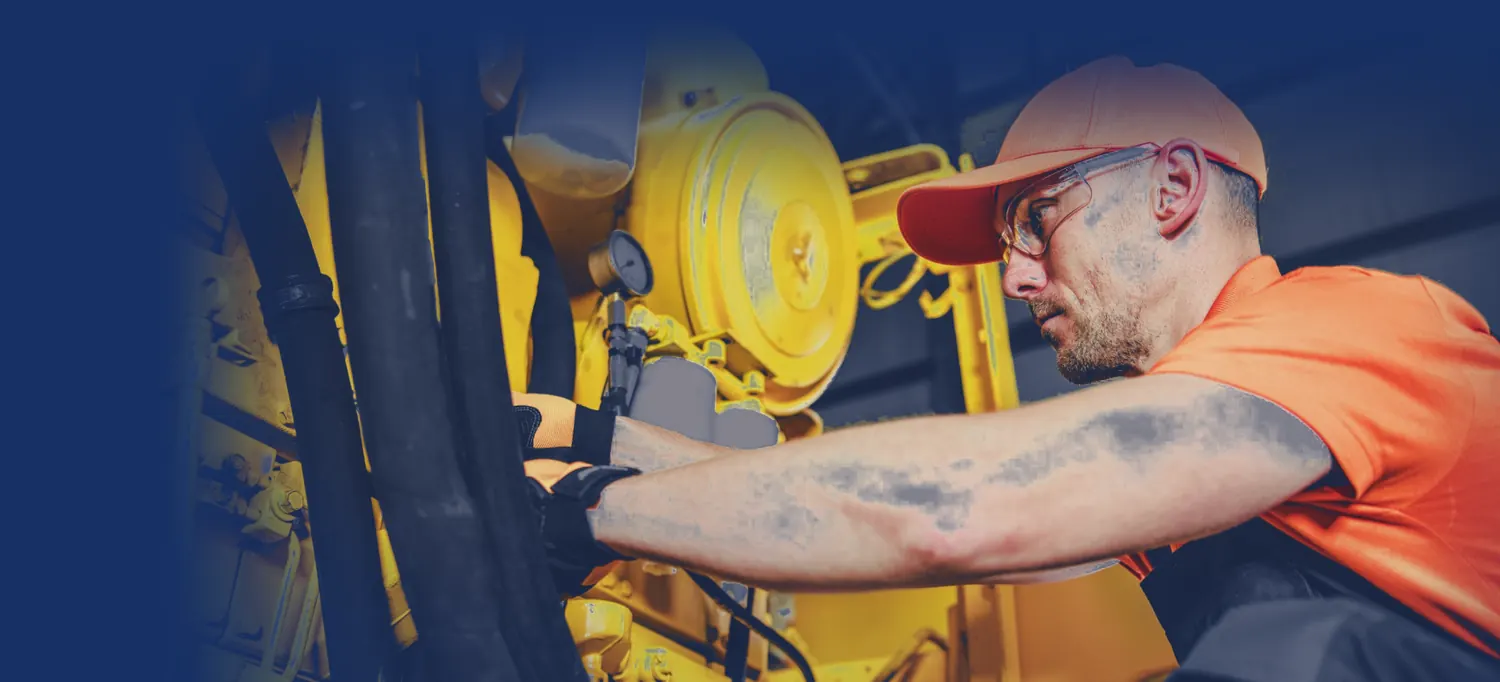 Technician in safety glasses working on a heavy equipment engine
