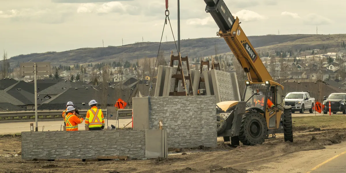 Crew in safety vests beside a SANY telehandler setting concrete wall panels