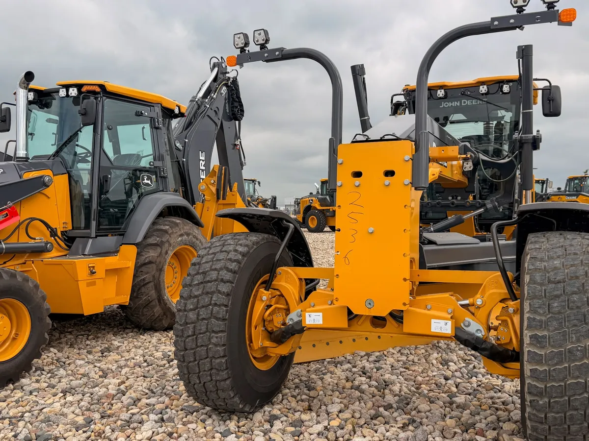John Deere backhoe and motor grader parked on a gravel lot