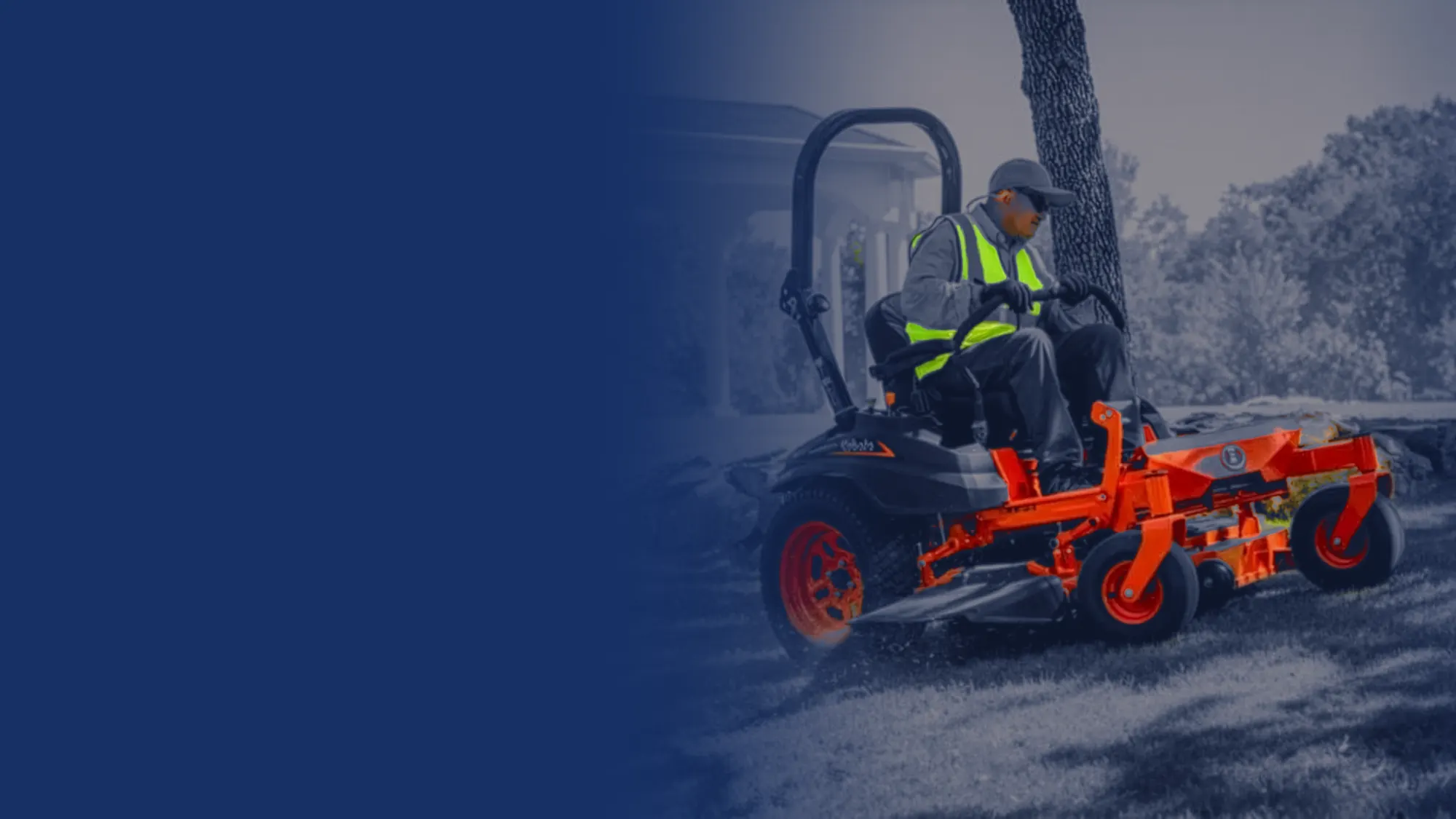 Landscaper in a safety vest mowing on a Kubota zero-turn mower beside a garden pavilion