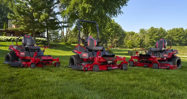Three Toro zero-turn mowers parked on a freshly mowed lawn