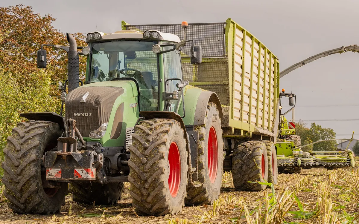 Fendt tractor and silage wagon working beside a forage harvester during corn harvest