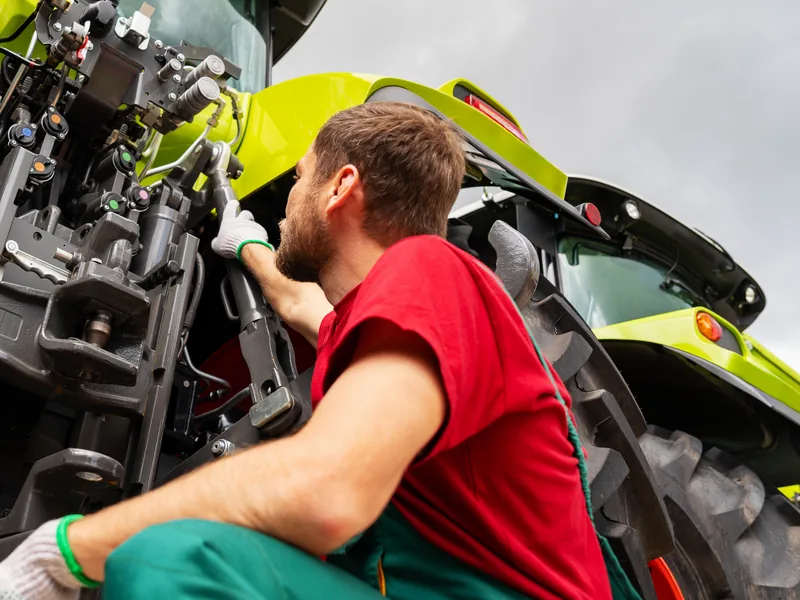 Technician working on the rear hitch of a large tractor