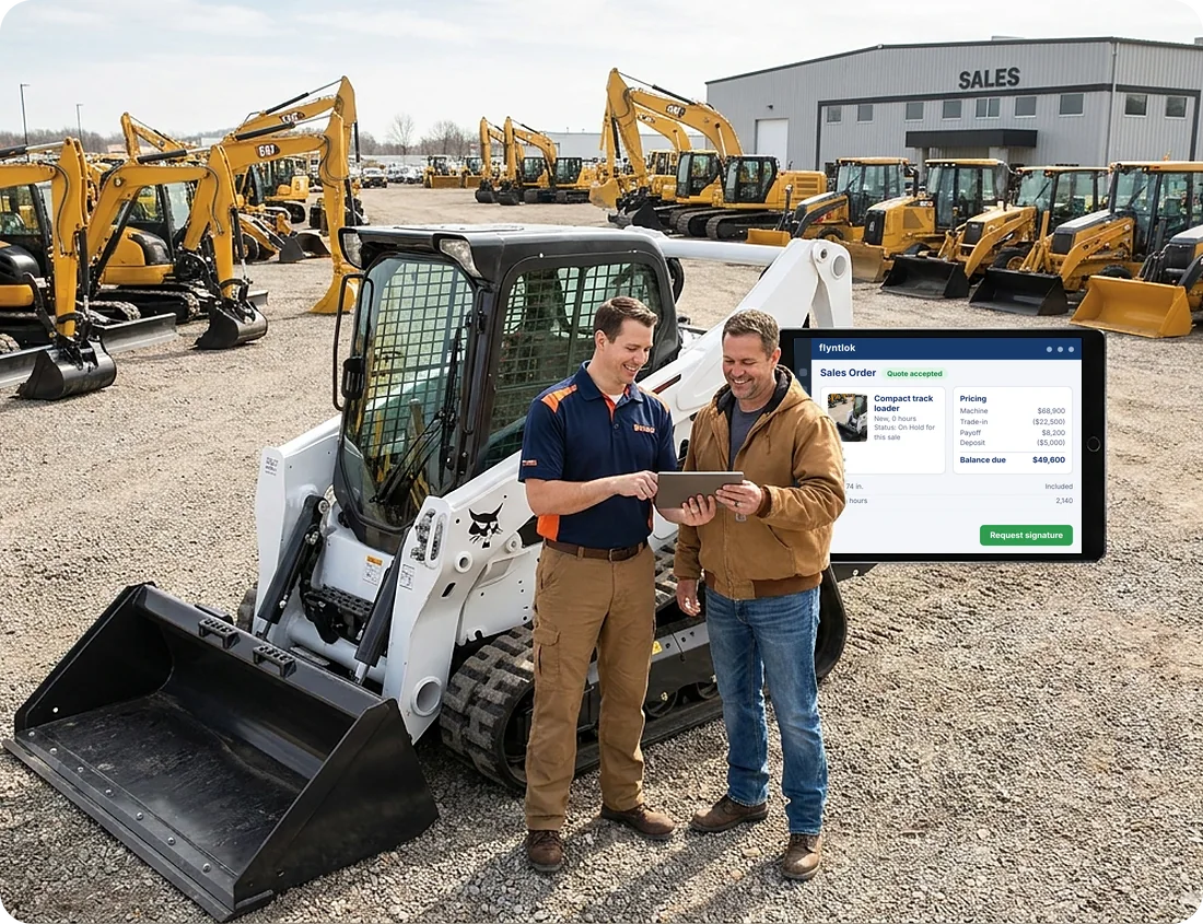 Salesman and customer reviewing a machine quote on a tablet beside a compact track loader on a dealer lot