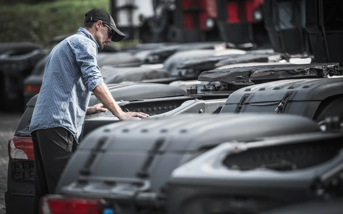 Technician inspecting a row of new truck cabs on a dealer lot