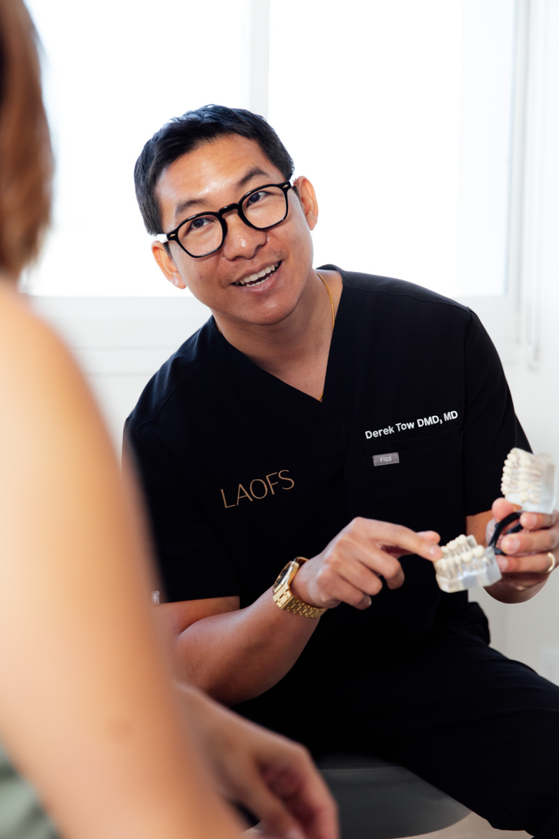 Dr. Tow walking a patient through a dental implant model.