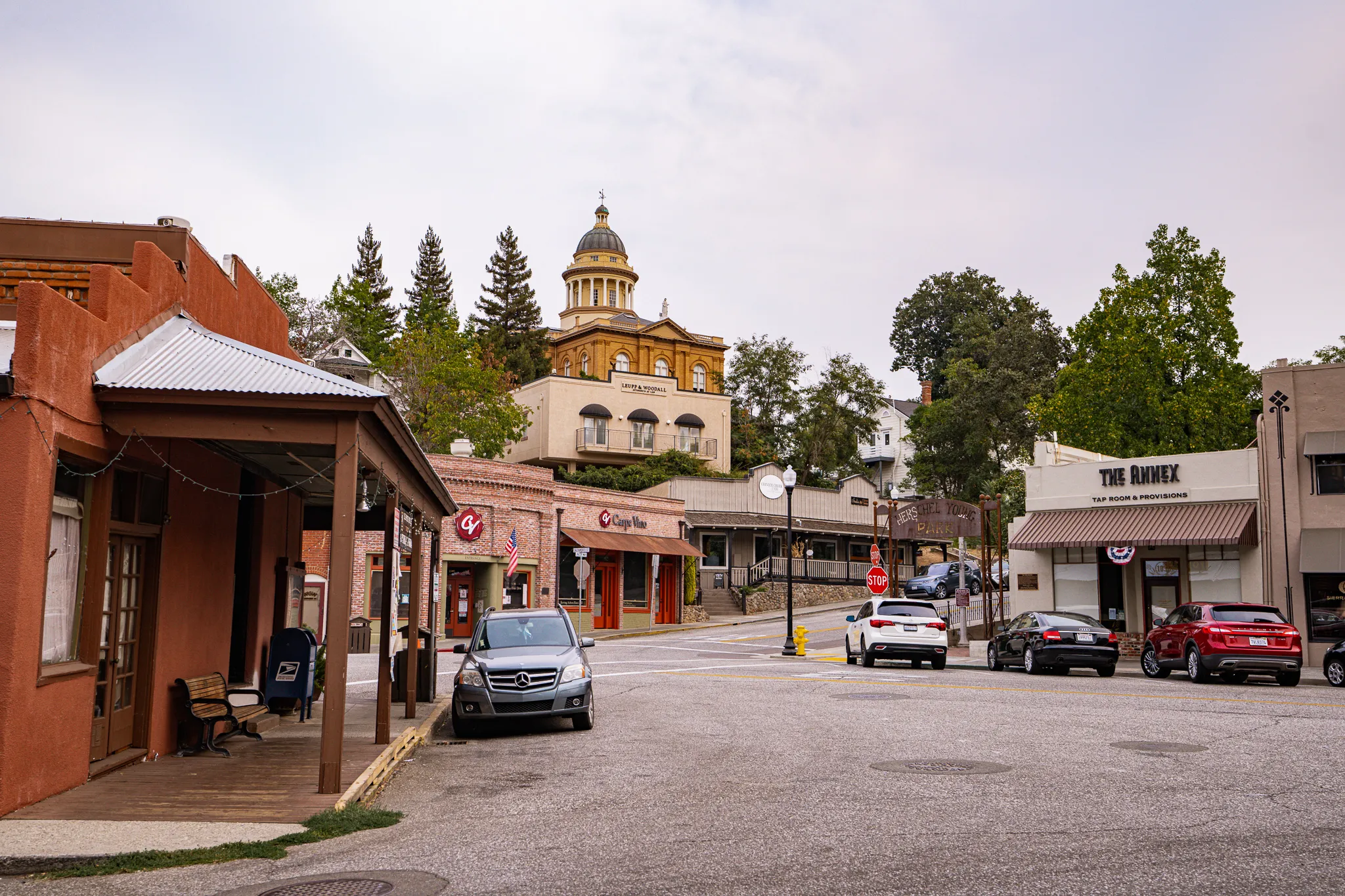 a small town street with cars parked on the side of the road