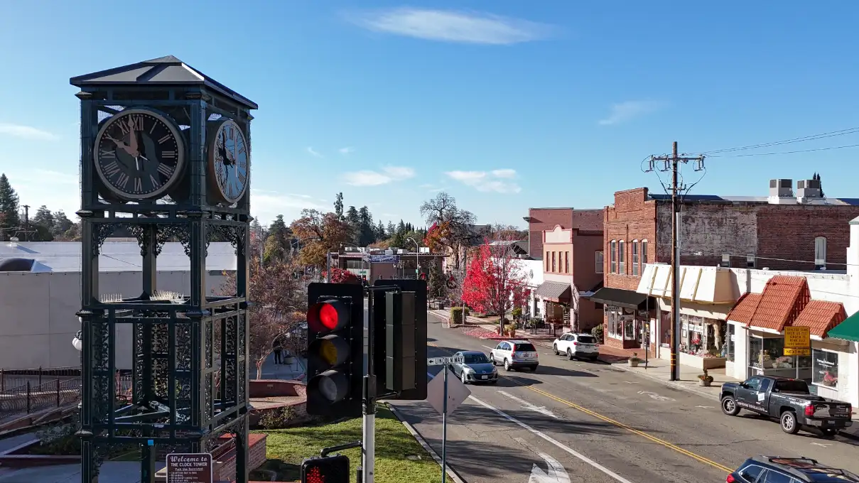 The iconic clock tower in downtown Auburn, CA overseeing a quiet intersection with local shops.