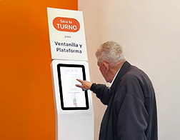 Person using self-service ticket kiosk for queue management in bank branch