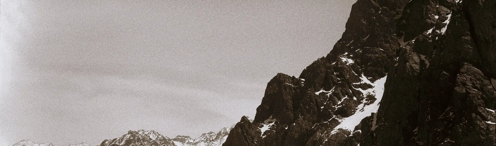 A greyscale mountain with light snow