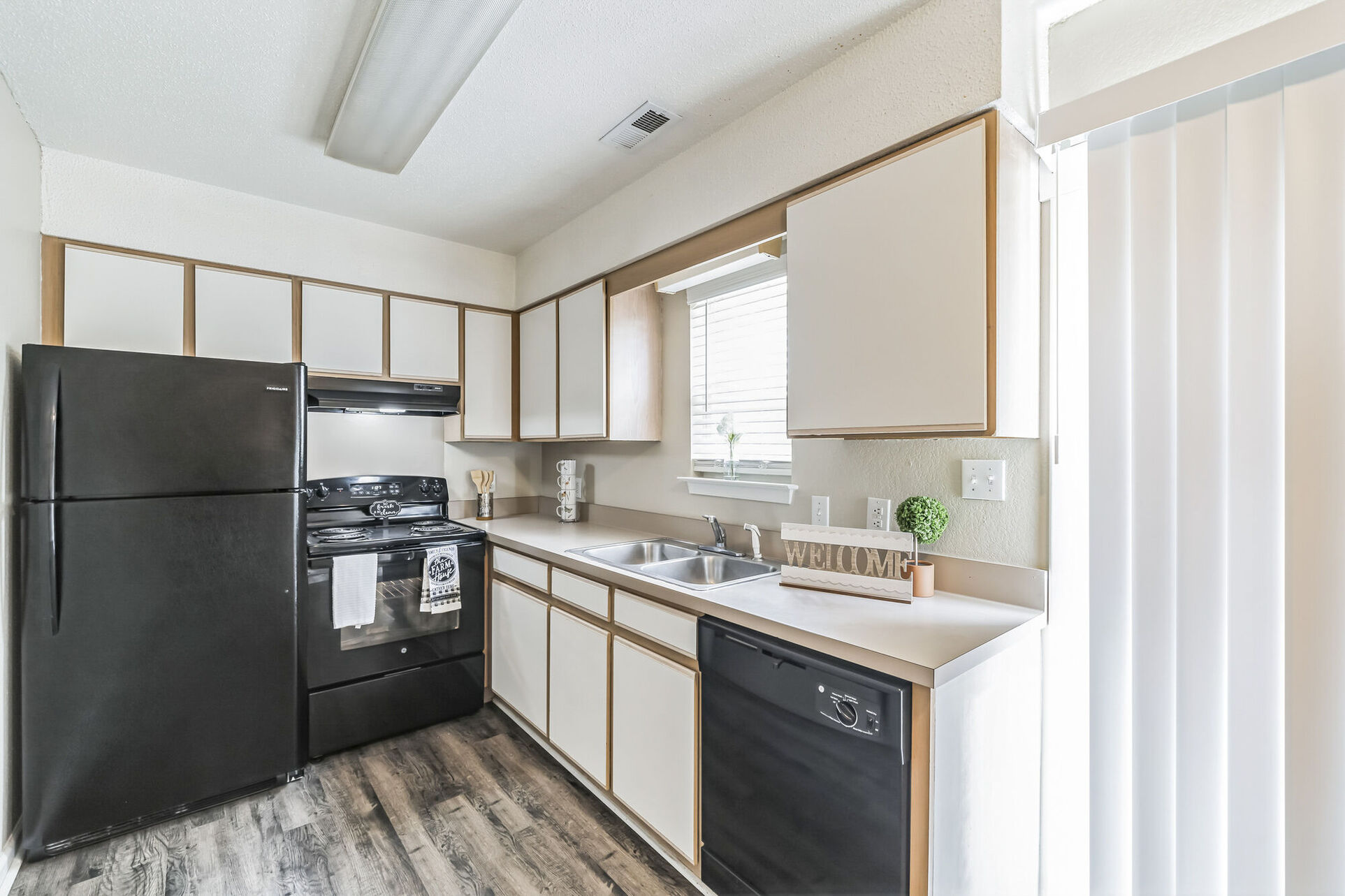 Kitchen with black appliances and white and brown wood cabinets